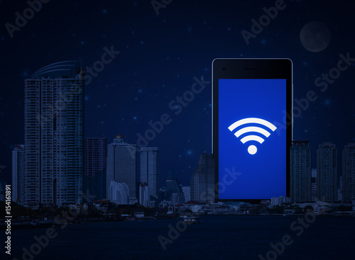 Wi-fi connection icon on modern smart phone screen with office city tower, river and fantasy night sky, Technology and internet concept