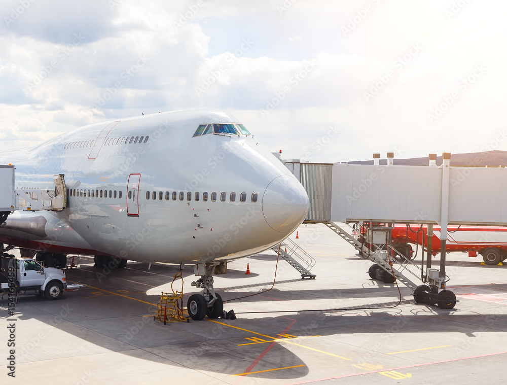 large passenger plane parked at airport ready to fly. The tanker, the tunnel on the background of sunlight large passenger plane parked at airport ready to fly. The tanker, the tunnel on the background of sunlight