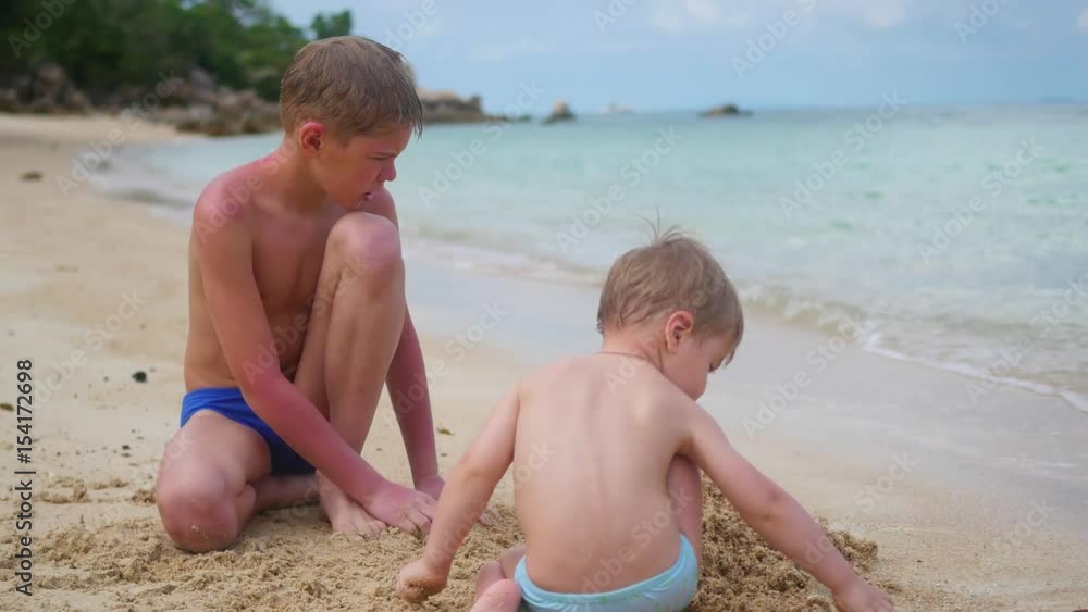 a young man plays with child on the beach. To make the sand molds a young man plays with child on the beach. To make the sand molds