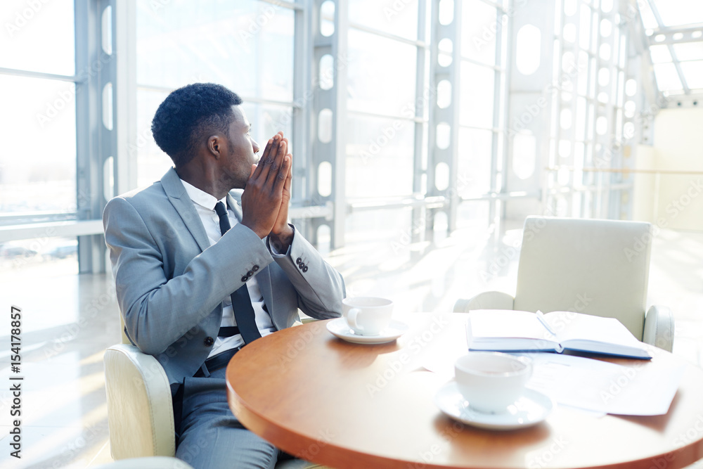 Inspired businesman sitting by table at coffee-break Inspired businesman sitting by table at coffee-break