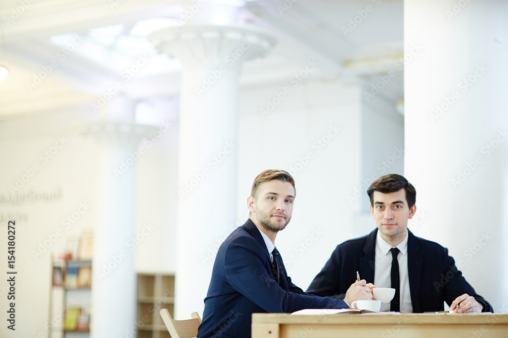 Successful brokers looking at camera while having meeting Successful brokers looking at camera while having meeting