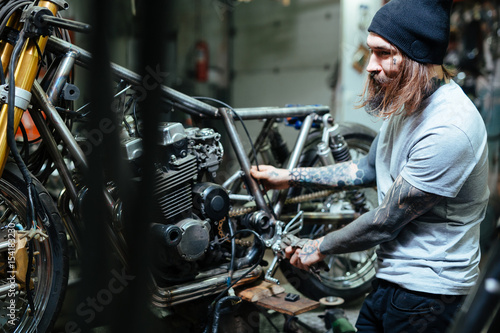 Hipster with tattoos repairing broken bikes