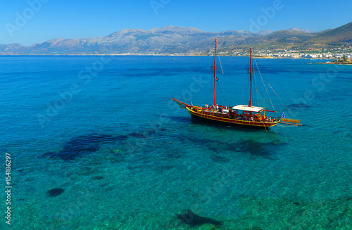 ship like pirate schooners with two masts for sails near the rocks of the coast of Crete