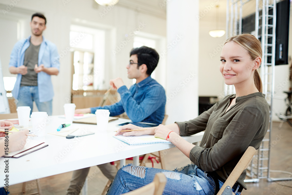 Obraz premium Pretty young designer making notes in notepad in working environment