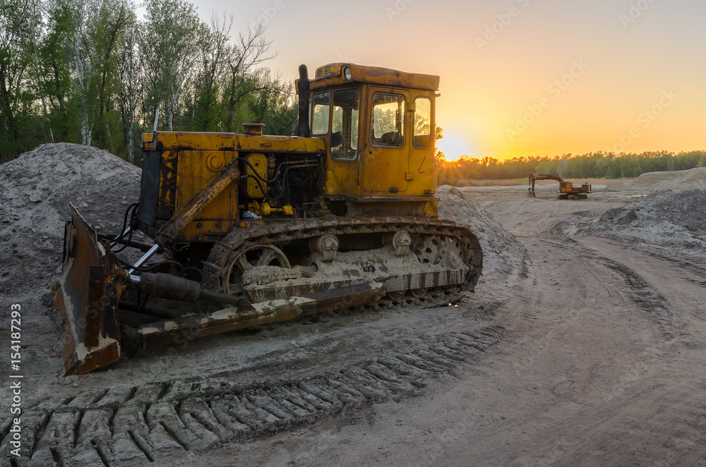 An old tractor with a large bucket extracts sand in a quarry An old tractor with a large bucket extracts sand in a quarry