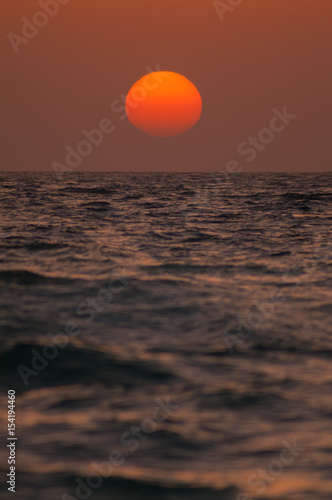 Fototapeta Naklejka Na Ścianę i Meble -  orange sun approaching horizon  over sea