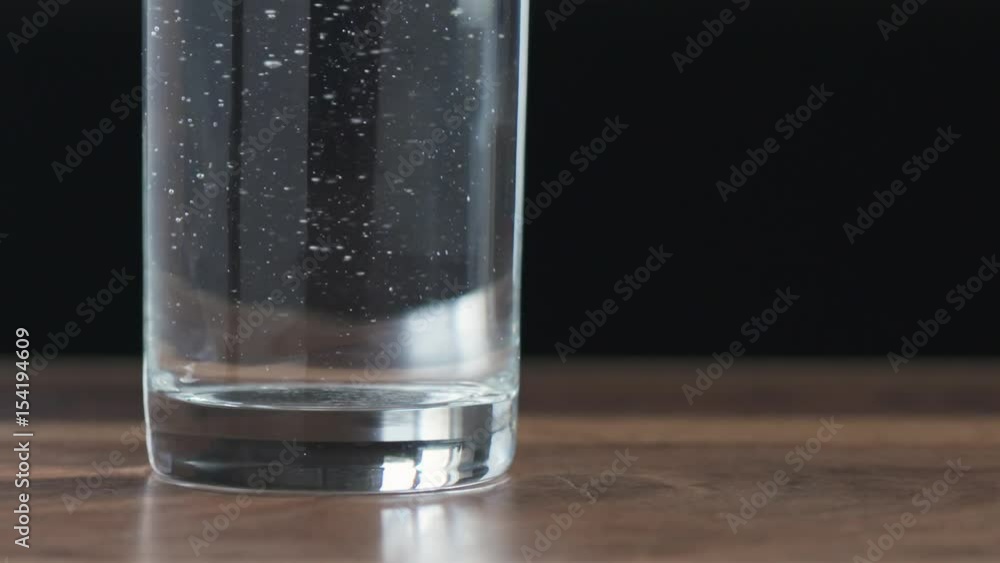 Slow motion of water in glass after pour on wood table closeup, 180fps prores footage Slow motion of water in glass after pour on wood table closeup, 180fps prores footage