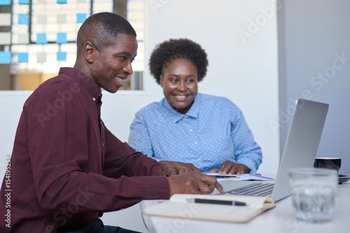 African business entrepeneurs working on a laptop in a white office © mavoimages