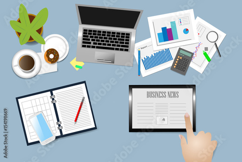 Top view of office desk with supplies, coffee cup and donuts on the plate. Hand is touching tablet with Business news.