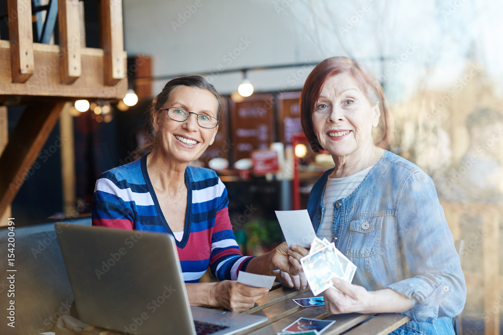 Smiling aged women with photos looking at camera Smiling aged women with photos looking at camera
