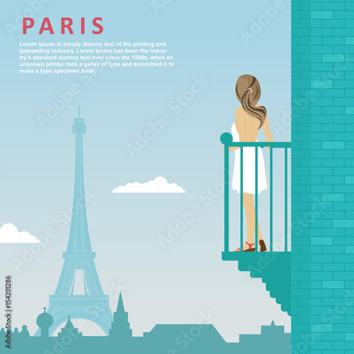 Young woman stands on balcony looking at Eiffel Tower in Paris