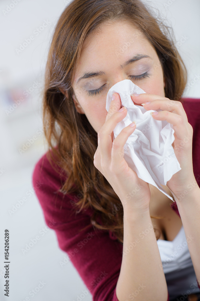 pretty woman sneezing on couch at home in living room pretty woman sneezing on couch at home in living room