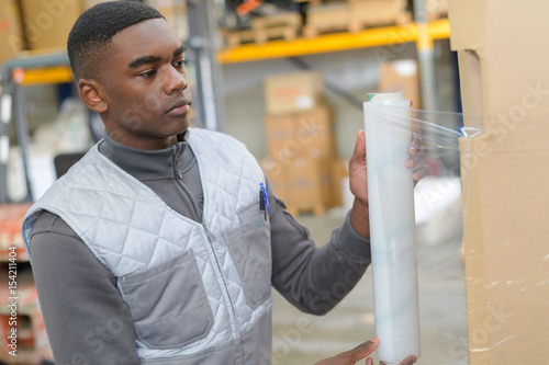 Young worker shrink wrapping pallet photo