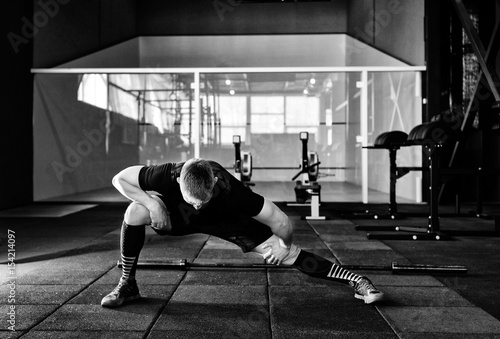Young man preparing muscles before training. Muscular athlete exercising in gym. Fit man stretching. Professional sportsman warming-up. Full body length portrait