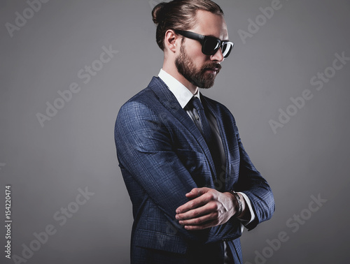 portrait of handsome fashion businessman  model dressed in elegant blue suit with sunglasses.posing on gray background in studio photo