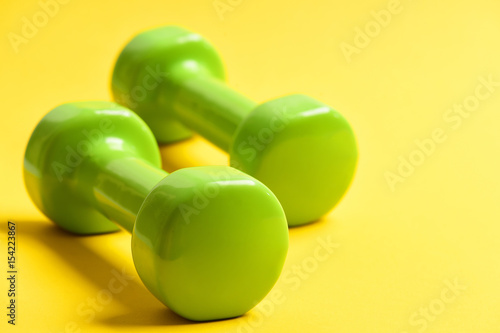 Dumbbells in green color on yellow
