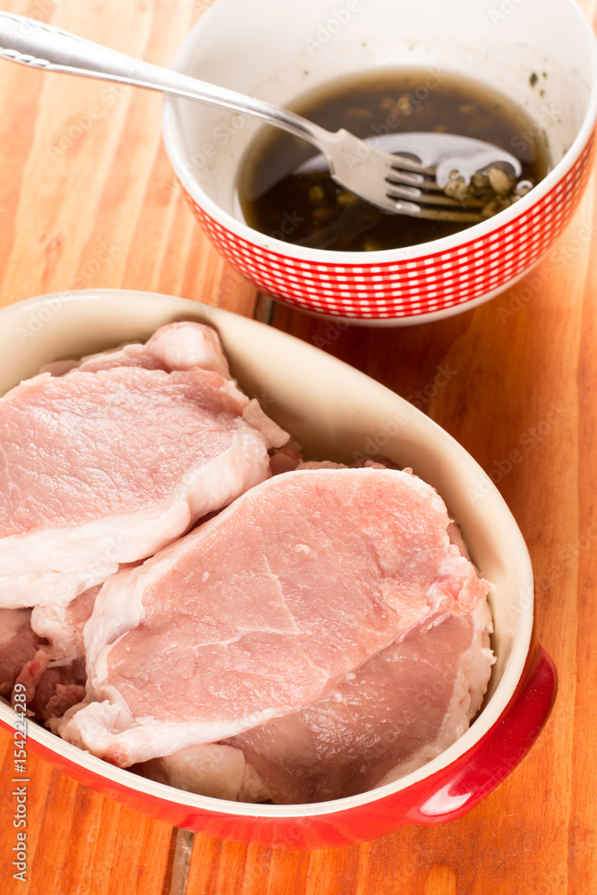 Fresh raw pork chops with marinade in the bowl. Selective focus Fresh raw pork chops with marinade in the bowl. Selective focus