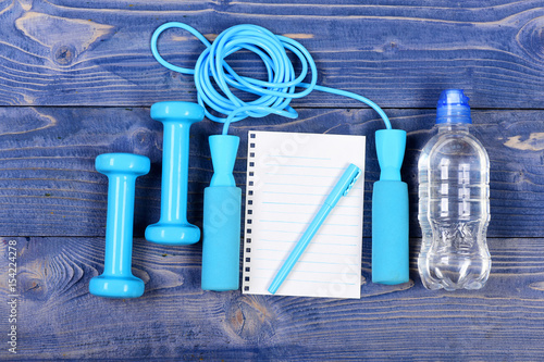 water bottle, notebook, skipping rope and dumbbells on blue vintage