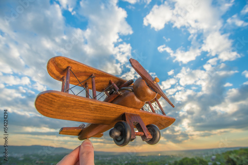 The hand hold wooden plane on the background of a blue sky