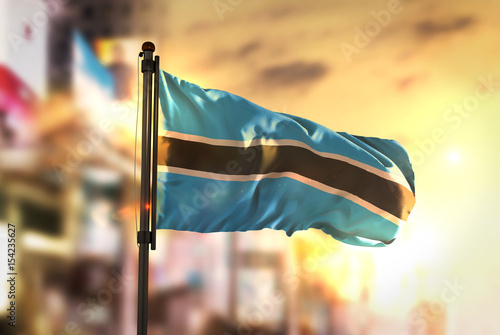 Botswana Flag Against City Blurred Background At Sunrise Backlight photo