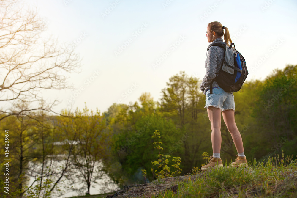 woman traveler standing on the cliff against river and blue sky woman traveler standing on the cliff against river and blue sky