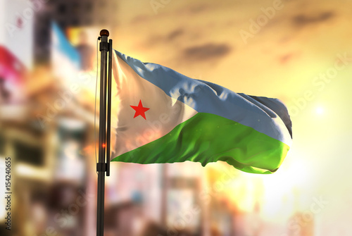 Djibouti Flag Against City Blurred Background At Sunrise Backlight photo