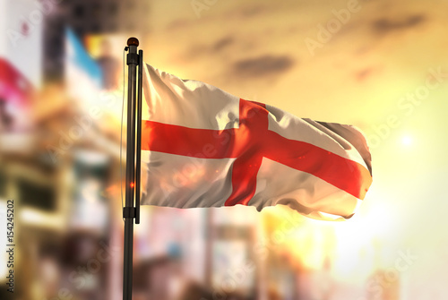 England Flag Against City Blurred Background At Sunrise Backlight