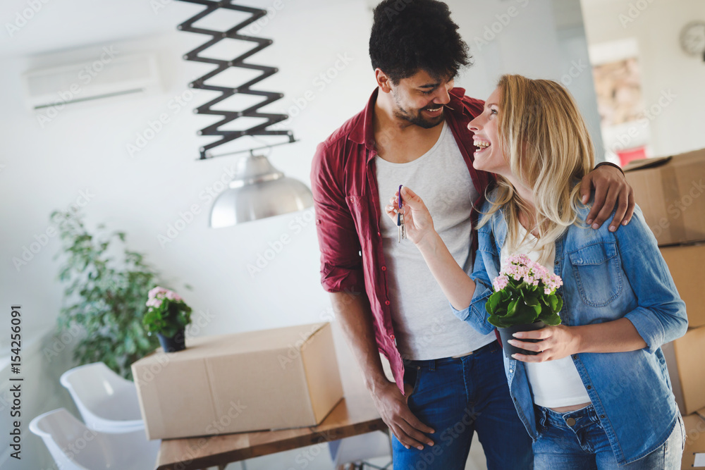 Young happy couple moving in new home and unpacking boxes Young happy couple moving in new home and unpacking boxes