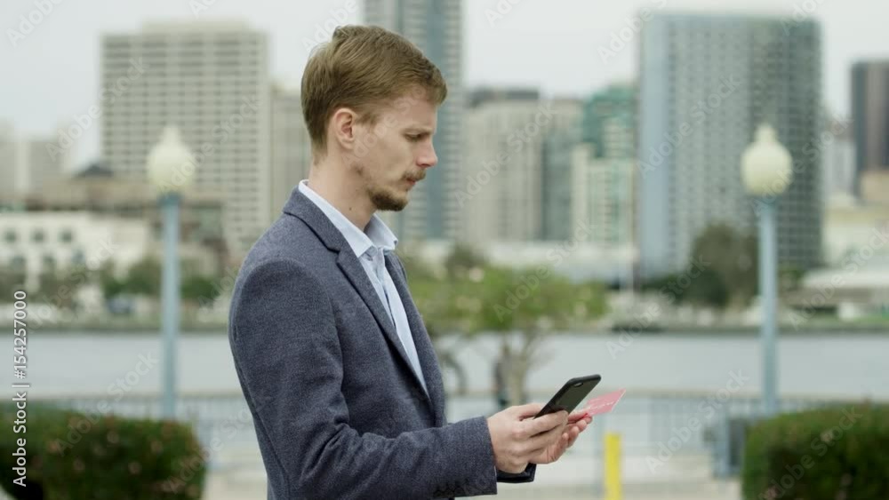 Young man is buying someting over the Internet on a street Young man is buying someting over the Internet on a street