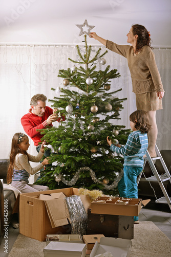 Familie dekoriert Weihnachtsbaum im Wohnzimmer