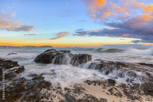 Ocean tide cascading over the rocks during sunrise at Currumbin Rock, Gold Coast