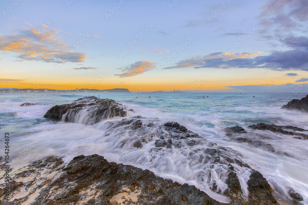 Ocean tide cascading over the rocks during sunrise at Currumbin Rock, Gold Coast