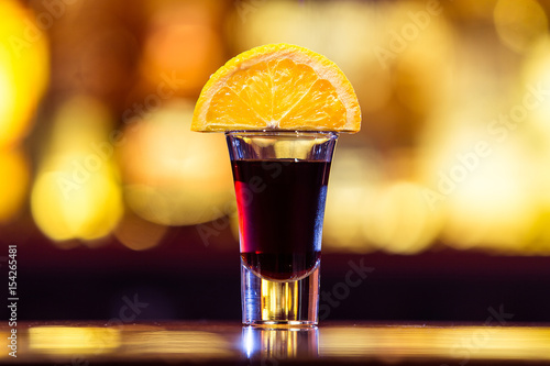 Black cocktail in a stack with a slice of orange