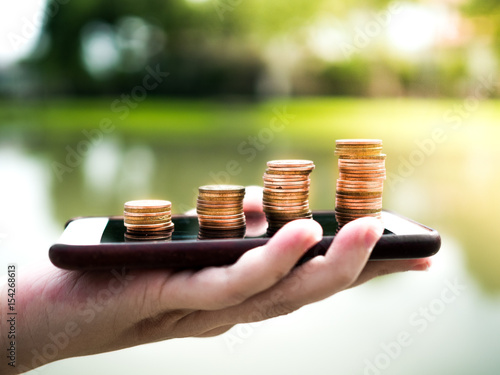 Close up stack of money coins on the mobile phone, business in eCommerce concept 