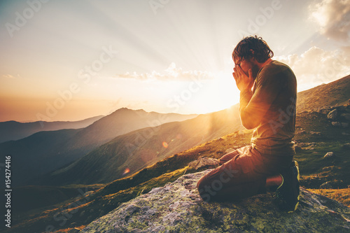 Man praying at sunset mountains Travel Lifestyle spiritual relaxation emotional meditating concept vacations outdoor harmony with nature landscape photo