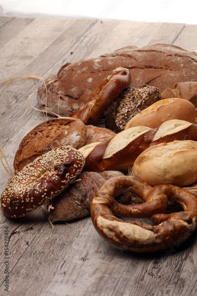 Different kinds of bread and bread rolls on board from above. Kitchen or bakery poster design. Different kinds of bread and bread rolls on board from above. Kitchen or bakery poster design.