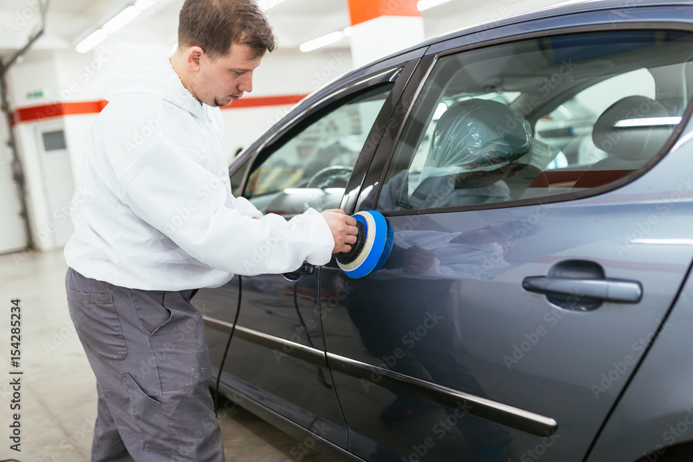 Car detailing - Man with orbital polisher in auto repair shop. Selective focus. Car detailing - Man with orbital polisher in auto repair shop. Selective focus.