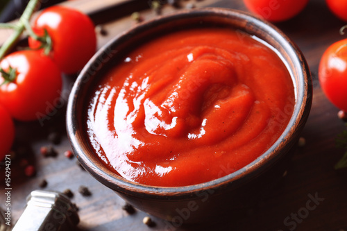 Delicious ketchup in bowl with ingredients on tray, closeup photo