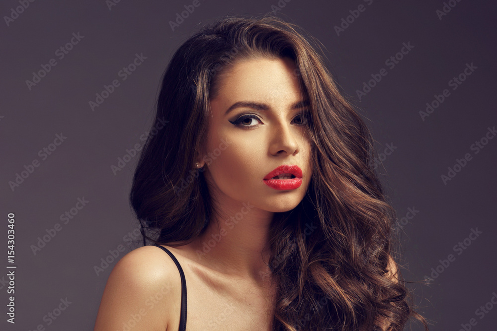 Fototapeta premium Pretty seductive girl in black silk nightie and white coat sitting and posing on white background. Fashion portrait.