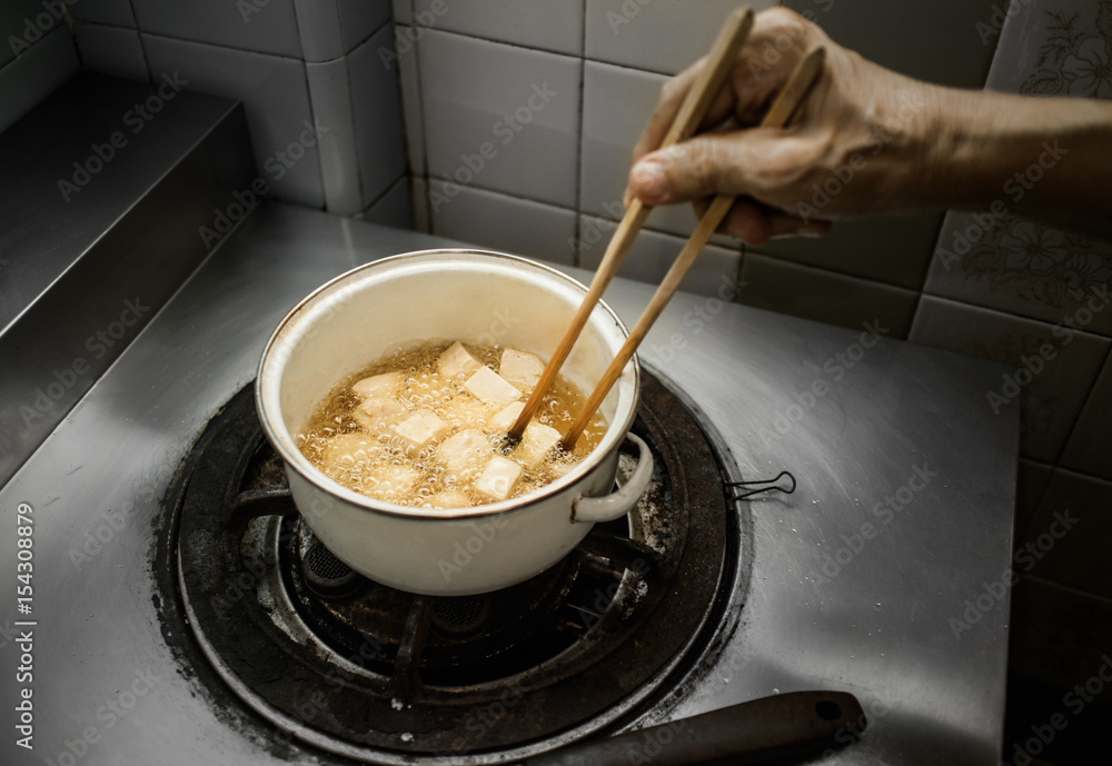 Cooking deep fried fish tofu in dim light kitchen Cooking deep fried fish tofu in dim light kitchen