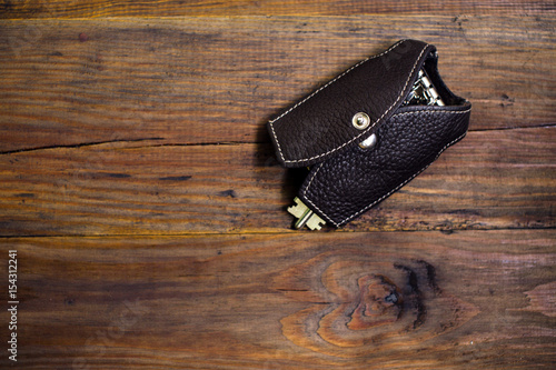 Leather key case with keys on the wood background. Dark background. Keychain. Key case in the form of a vest