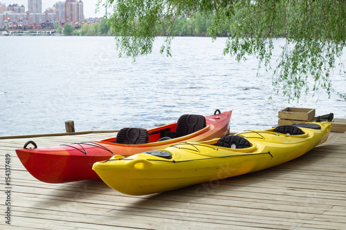 Two kayaking boats on wooden deck at station near lake