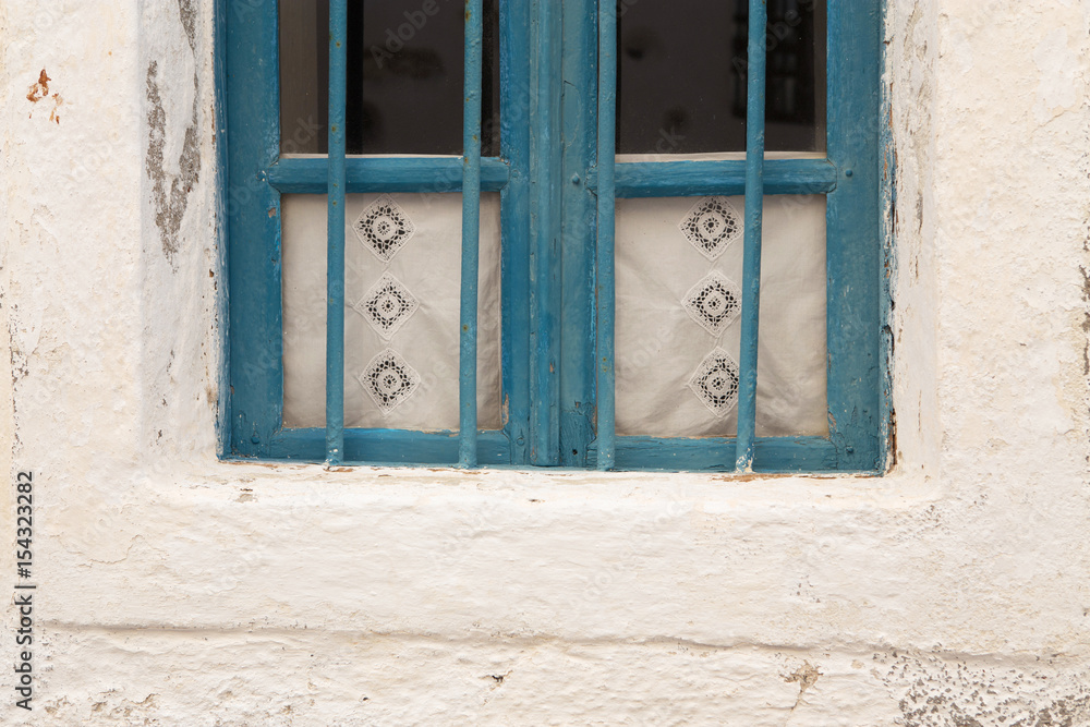 Blue painted window with handmade lace curtains behind. Santorini, Greece