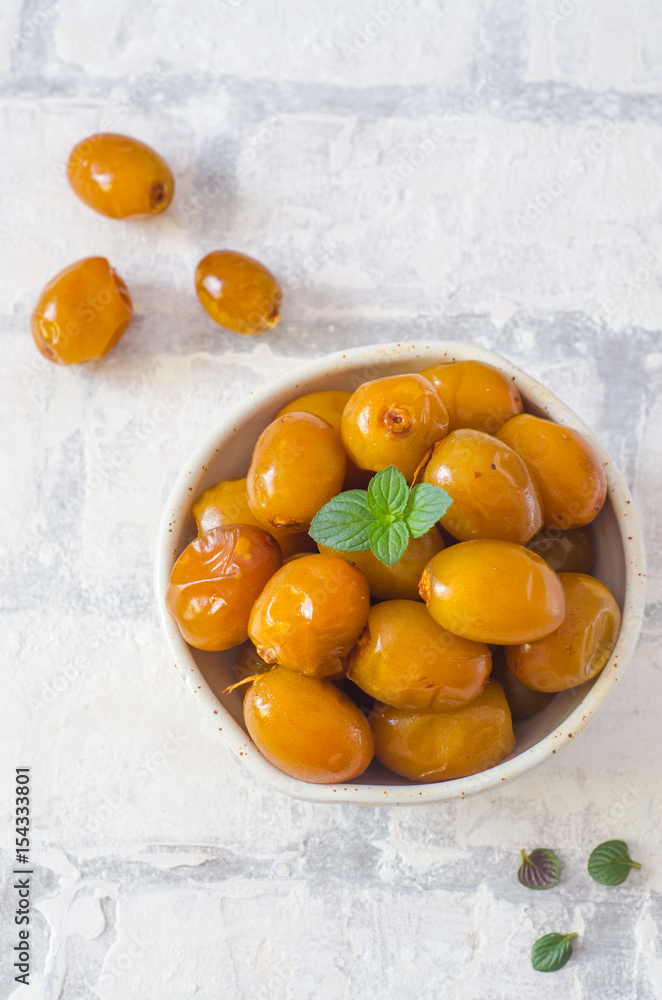 Raw fresh dates and green mint in a bowl on brick wall background close up. Selective focus. Raw fresh dates and green mint in a bowl on brick wall background close up. Selective focus.