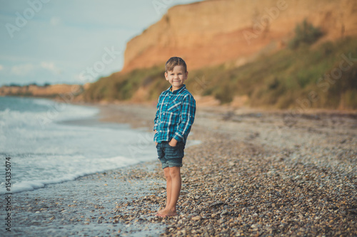 Portrait of happy boy standing alone at beach photo