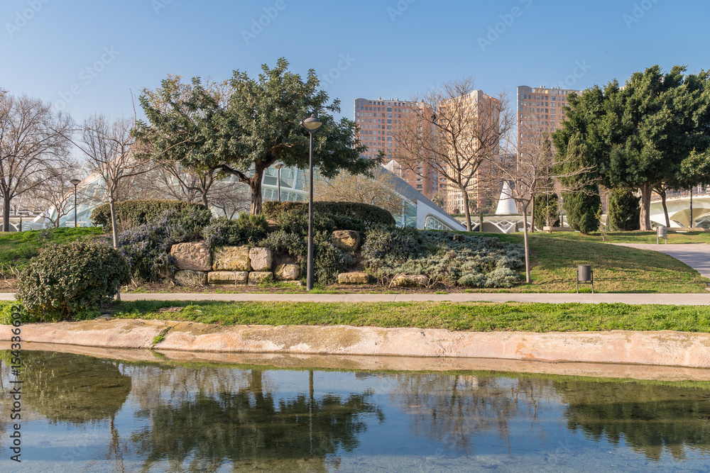 Gardens in the old dry riverbed of the Turia river in Valencia, water reflection. Beautiful landscape leisure and sport area with trees, grass and water mirror, Spain