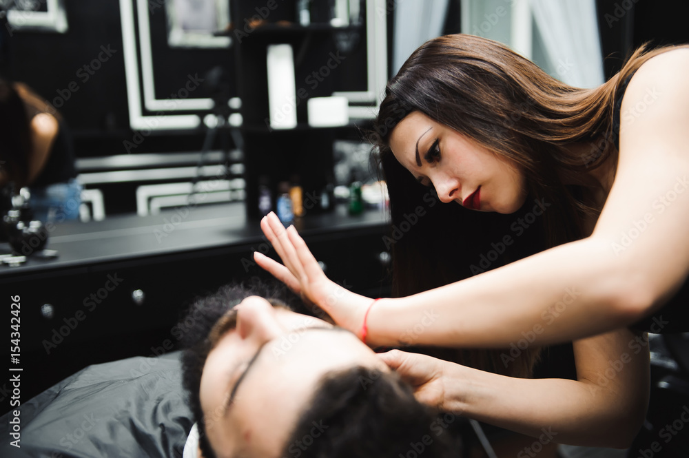 Fototapeta premium Master cuts hair and beard of men in the barbershop, hairdresser makes hairstyle for a young man
