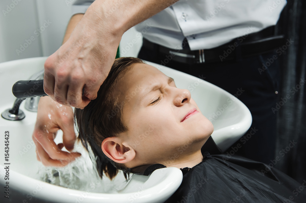 a boy is washed by the hairdresser in the barbershop a boy is washed by the hairdresser in the barbershop