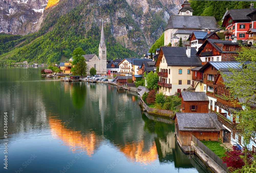 Classic postcard view of famous Hallstatt lakeside town reflecting in Hallstattersee lake in the Austrian Alps in scenic morning light on a beautiful sunny day in summer, Salzkammergut region, Austria
