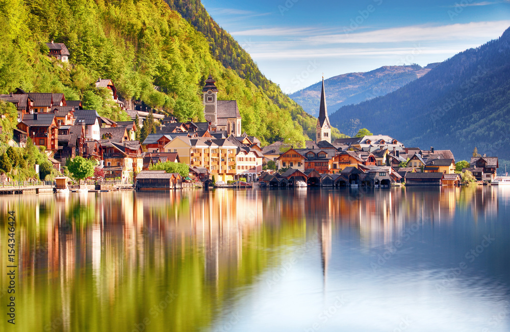 Classic postcard view of famous Hallstatt lakeside town reflecting in Hallstattersee lake in the Austrian Alps in scenic morning light on a beautiful sunny day in summer, Salzkammergut region, Austria